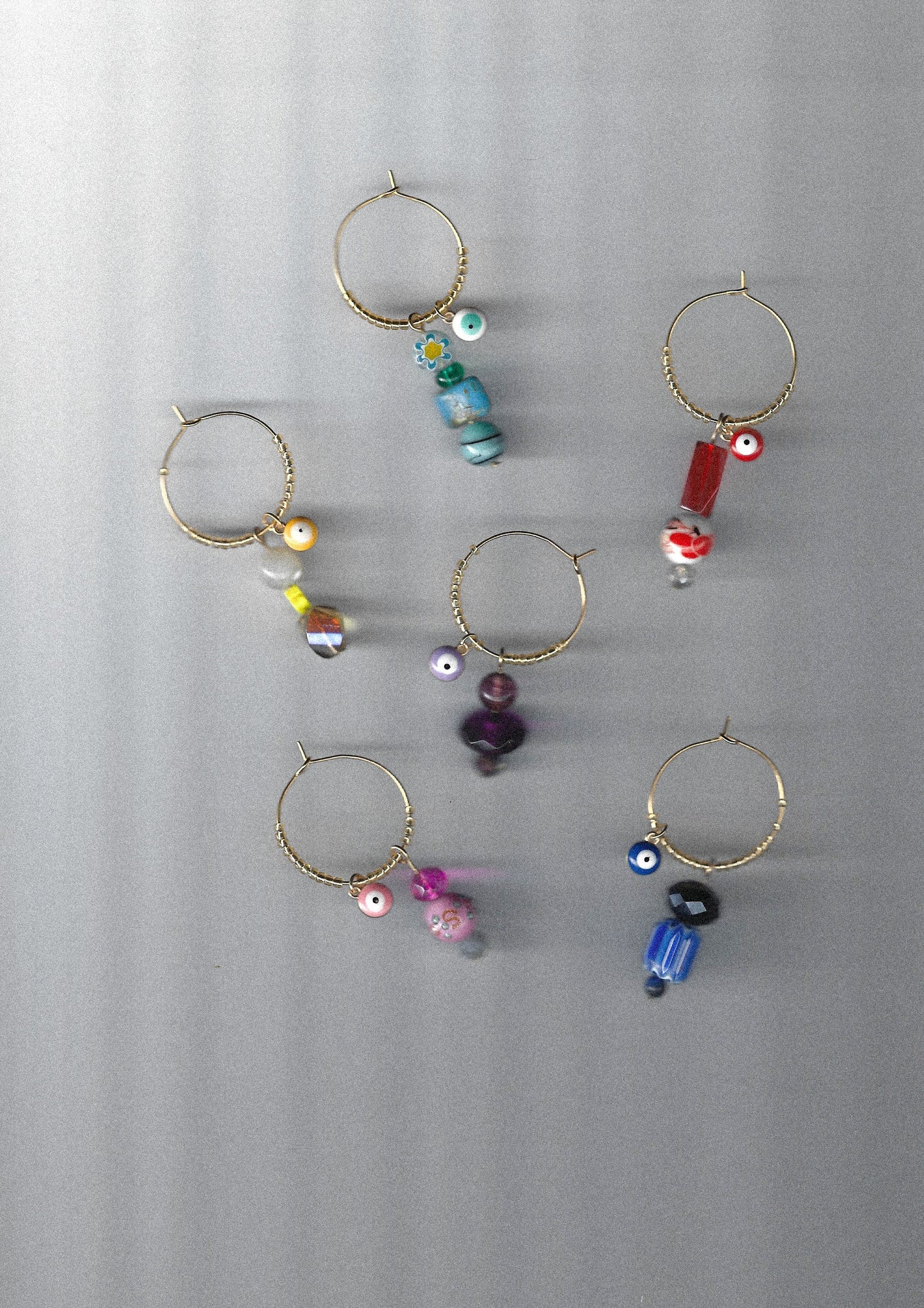Set of gold wine charms with colorful beads and evil eye charms on a gray background