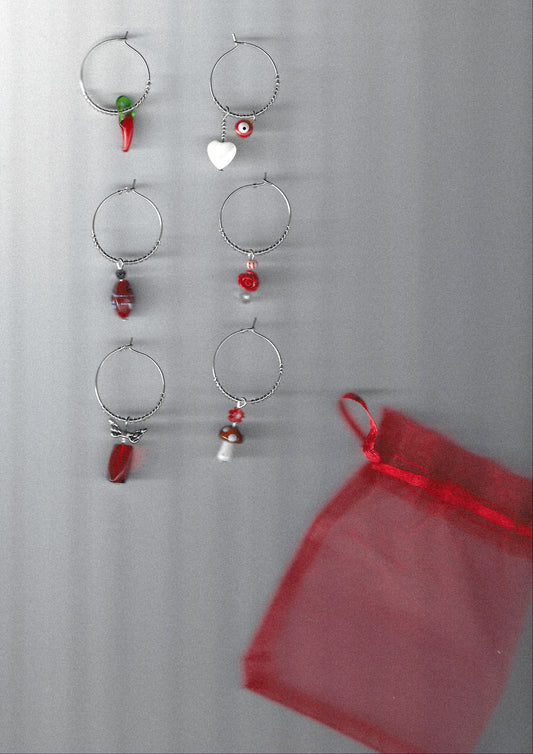 Set of silver hoop wine charms with red beads on a gray background