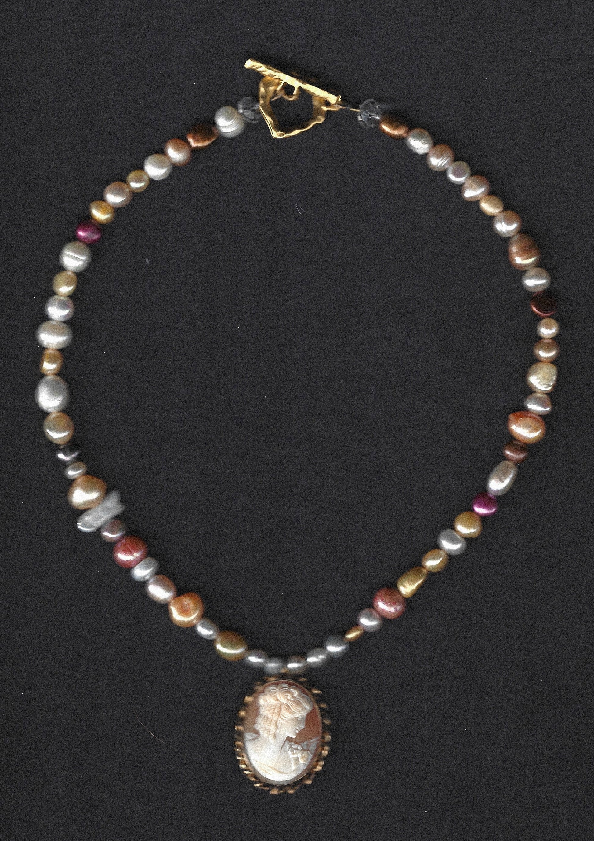 Pearl necklace with a cameo pendant on a black background