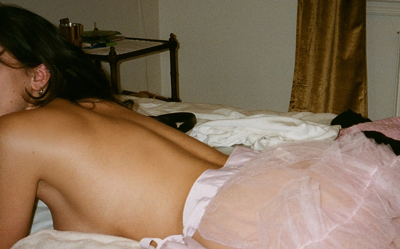 Person in a pink tutu lying on a bed with a blurred background