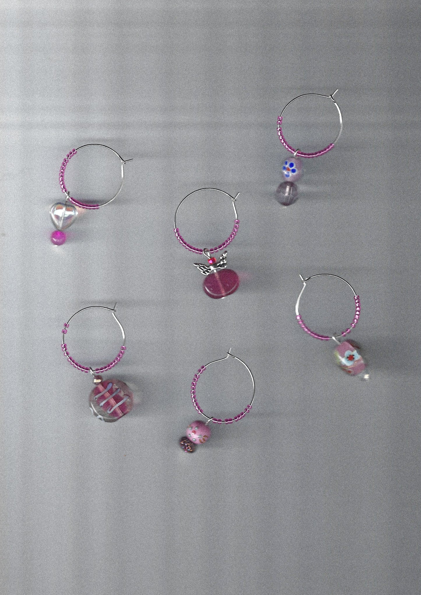 Set of pink and silver wine glass charms on a metallic surface