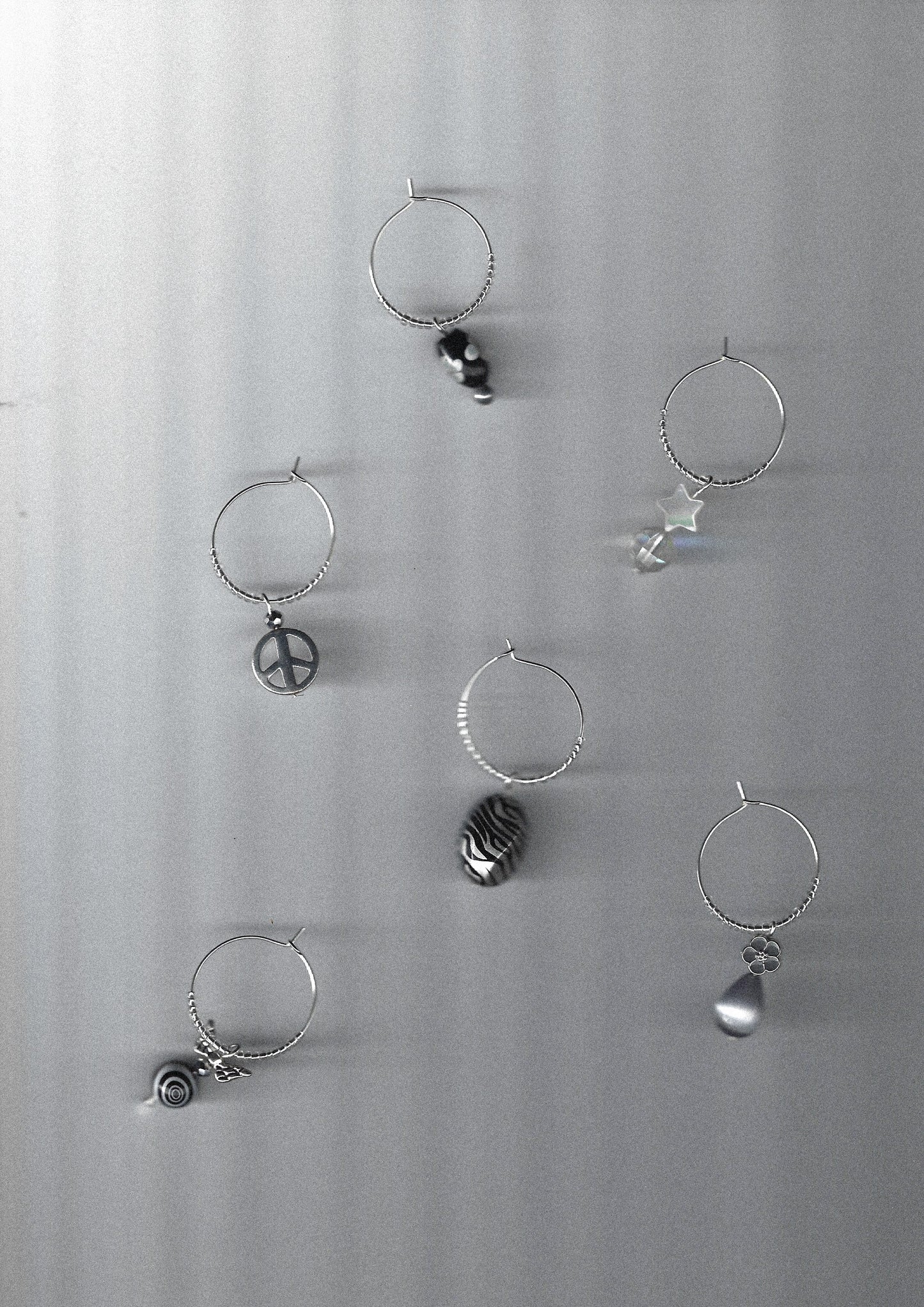 Set of silver wine glass charms with various black and white designs on a gray background